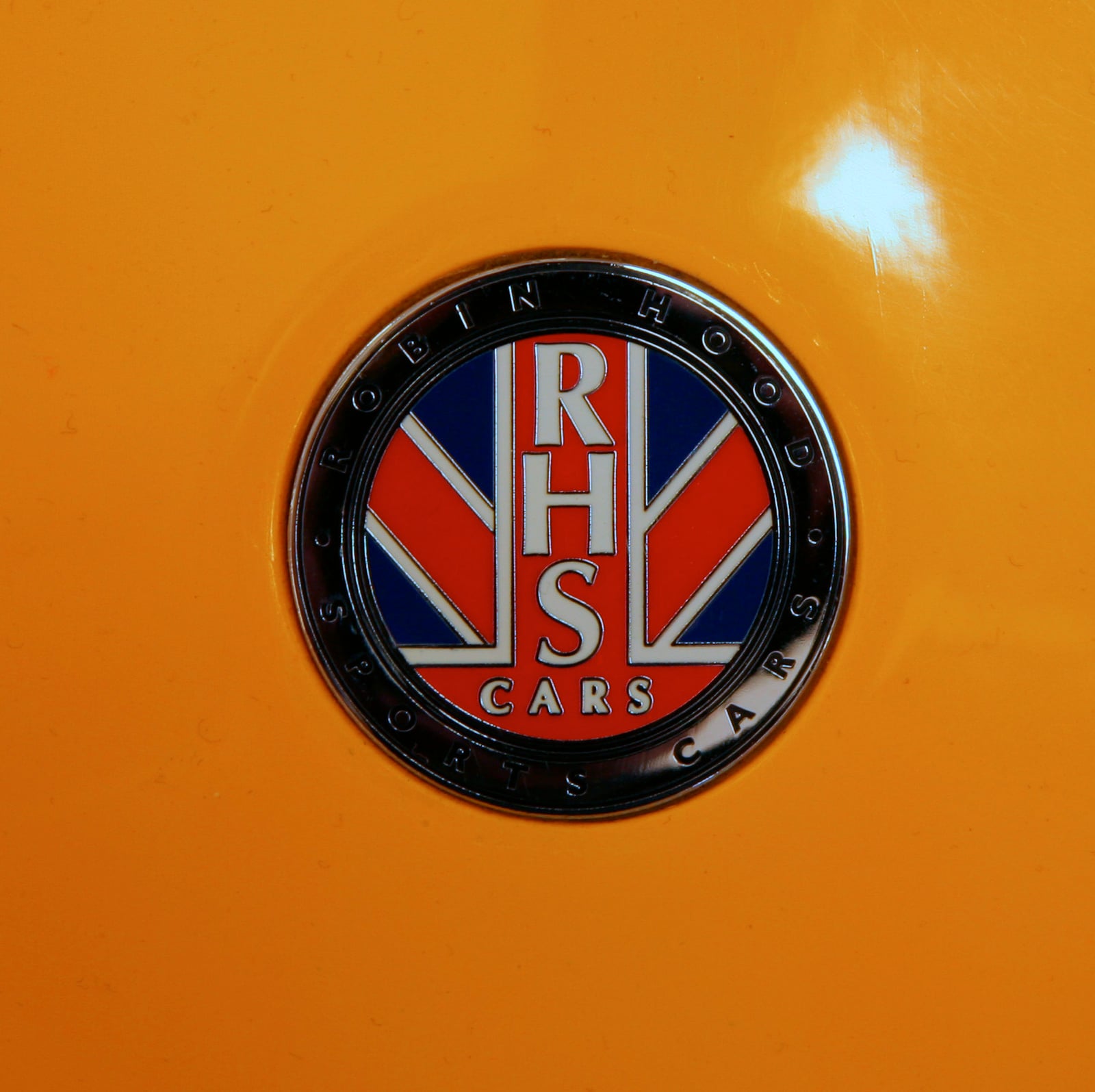 A close-up of the RHS Cars badge with a Union Jack on the orange bodywork of a Robin Hood