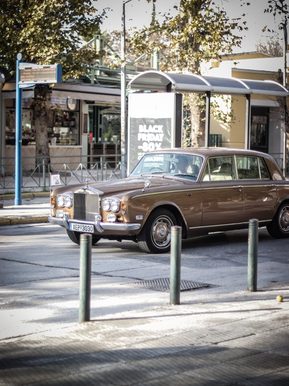 A gold Rolls-Royce Silver Shadow parked on a city street corner