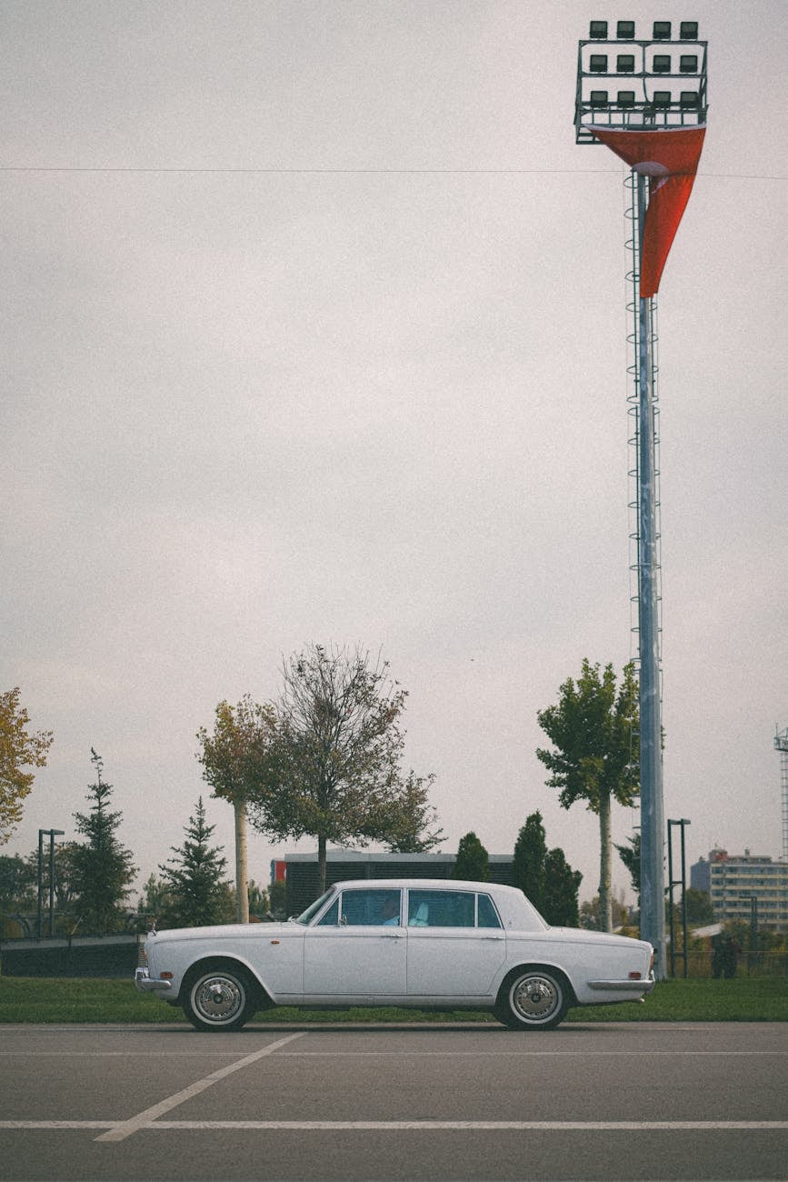A white Rolls-Royce Silver Shadow parked in an empty floodlit car park