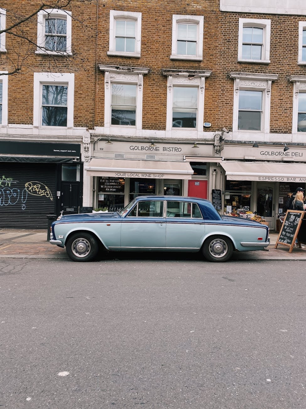 A blue Rolls-Royce Silver Shadow parked on a street in side view