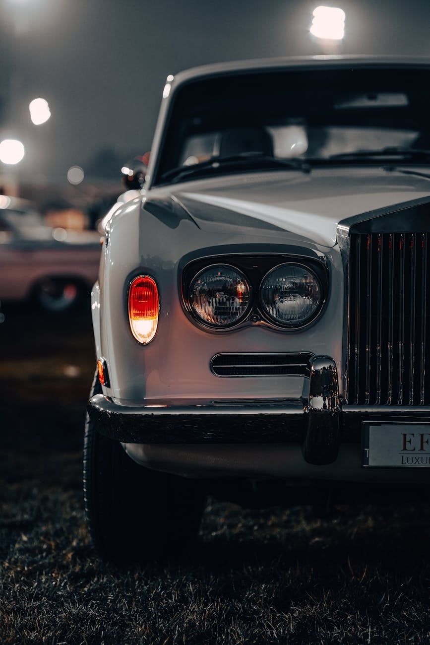 The headlamps and grille of a white Rolls-Royce Silver Shadow at night