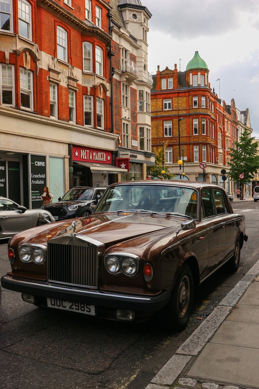 A brown Rolls-Royce Silver Shadow II parked on a London street with red-brick buildings behind