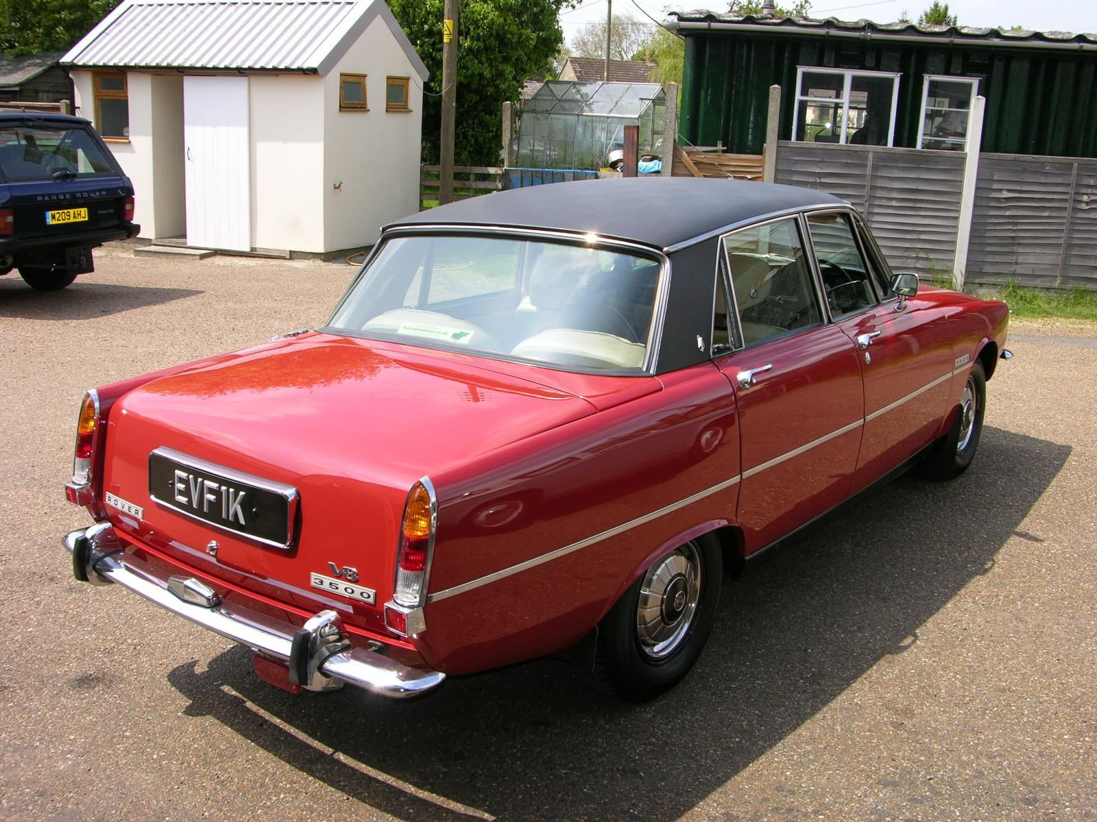 A red Rover P6 3500 V8 with a black vinyl roof photographed from the rear three-quarter, UK registration EVF 1K