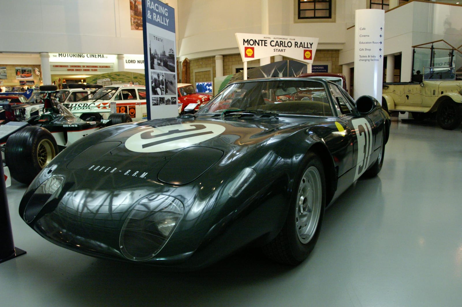 The dark green Rover-BRM gas-turbine Le Mans car in the main hall of the National Motor Museum at Beaulieu, with rally and racing cars behind
