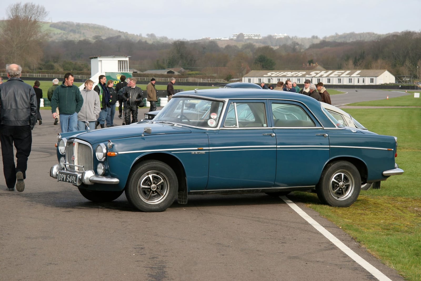 A blue and grey two-tone Rover P5B saloon in side profile at a motor circuit paddock