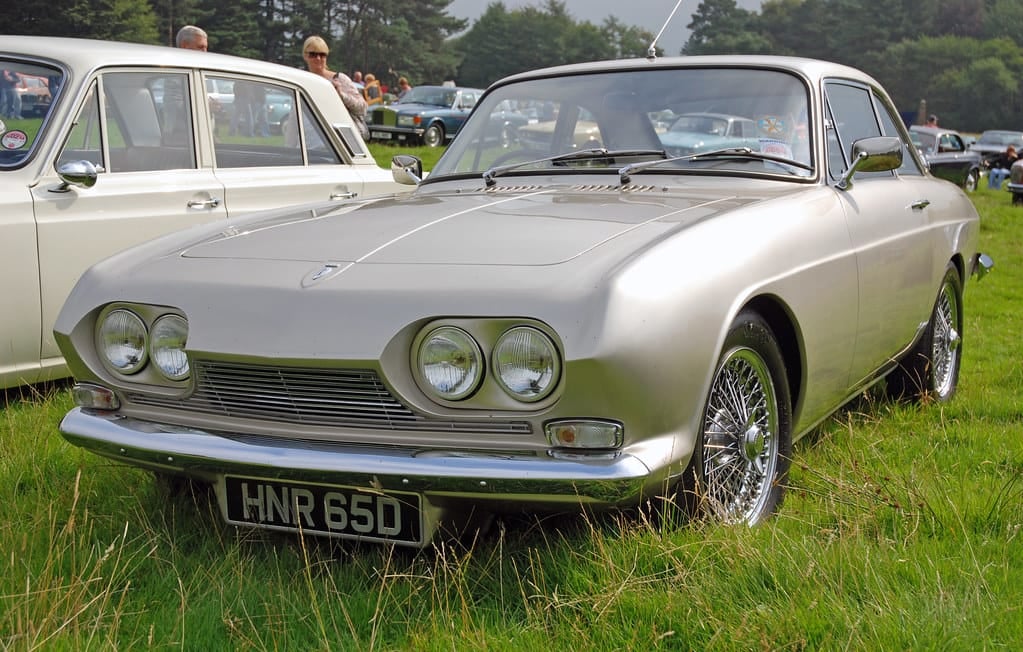 A silver Reliant Scimitar GT SE4 coupe on grass, front three-quarter view, UK registration HNR 65D