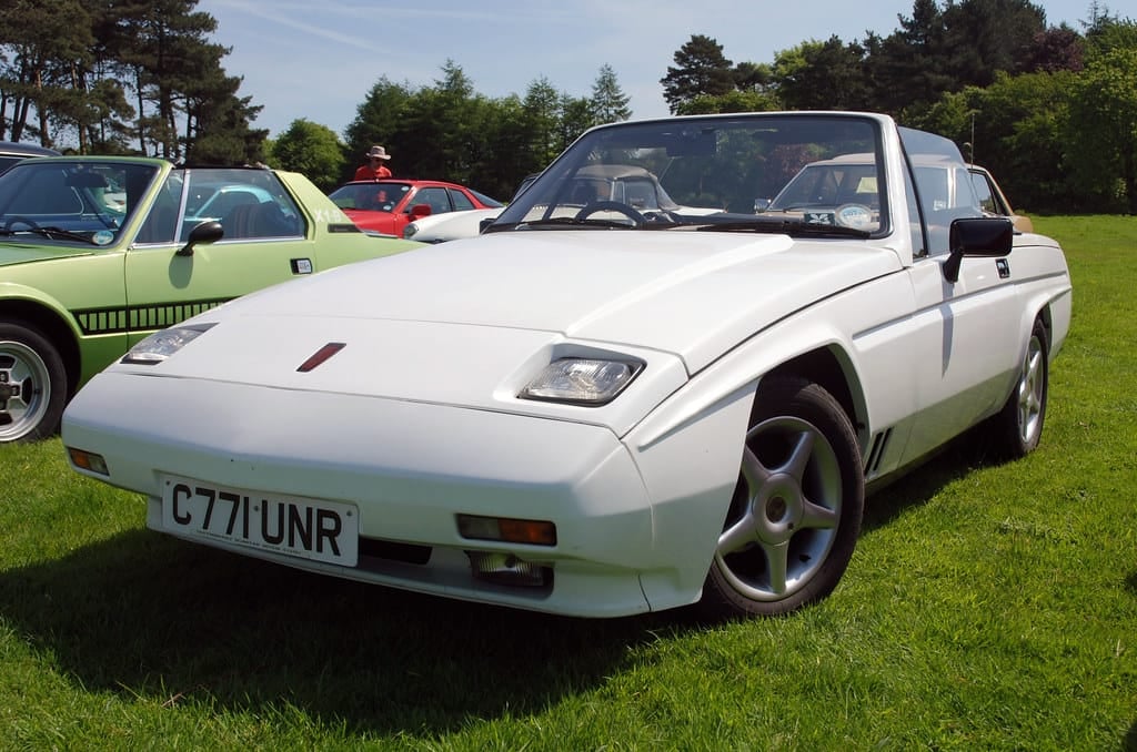 A white Reliant Scimitar SS1 with the top down on grass, front three-quarter view, UK registration C771 UNR