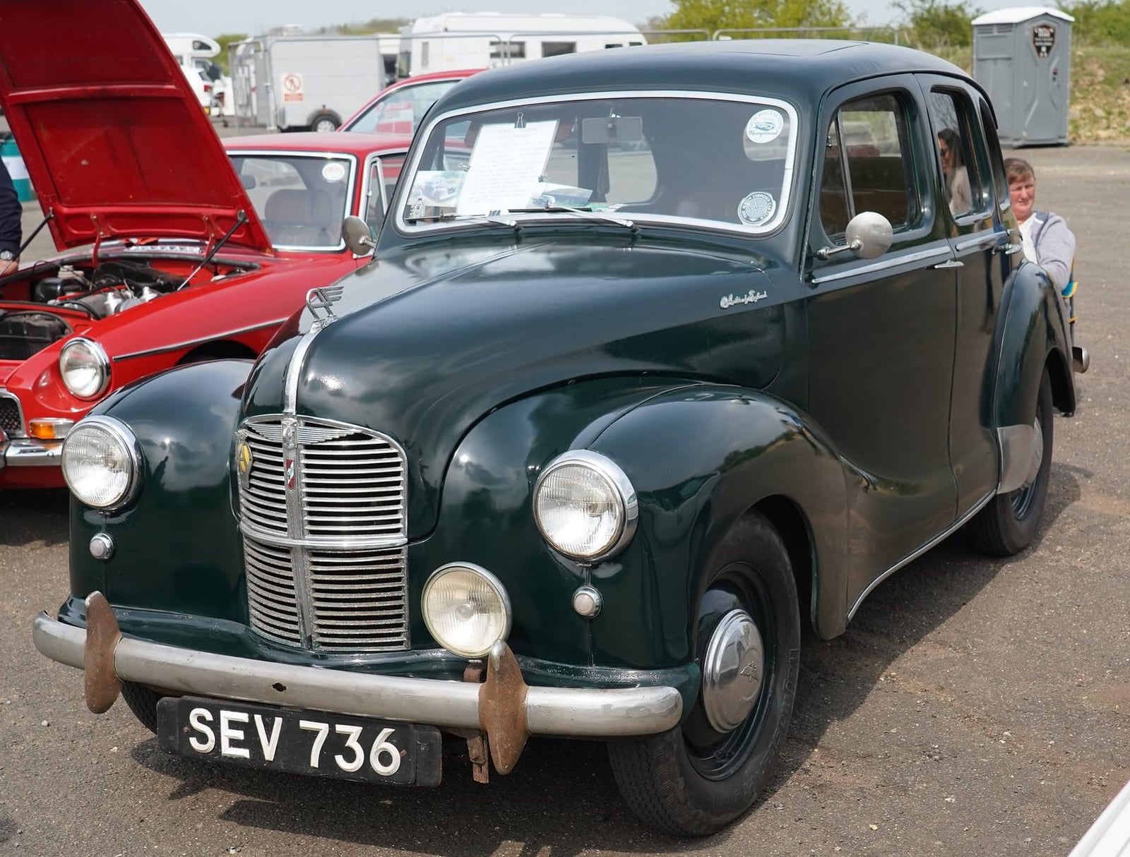 A dark green 1941 Austin Ten wartime saloon at a show, front view, UK registration SEV 736
