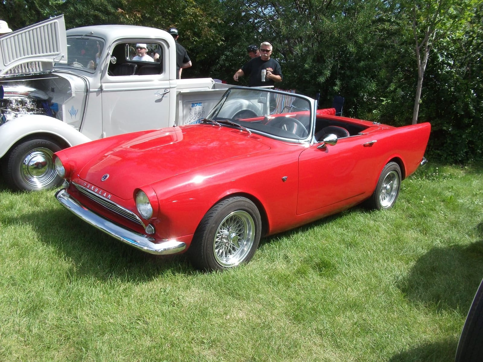 A white Sunbeam Alpine with a hardtop parked on grass in front of a castle