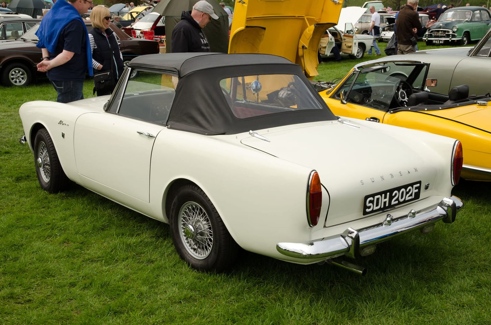 A white 1967 Sunbeam Alpine Series V with its black hood raised, on grass, UK registration SDH 202F