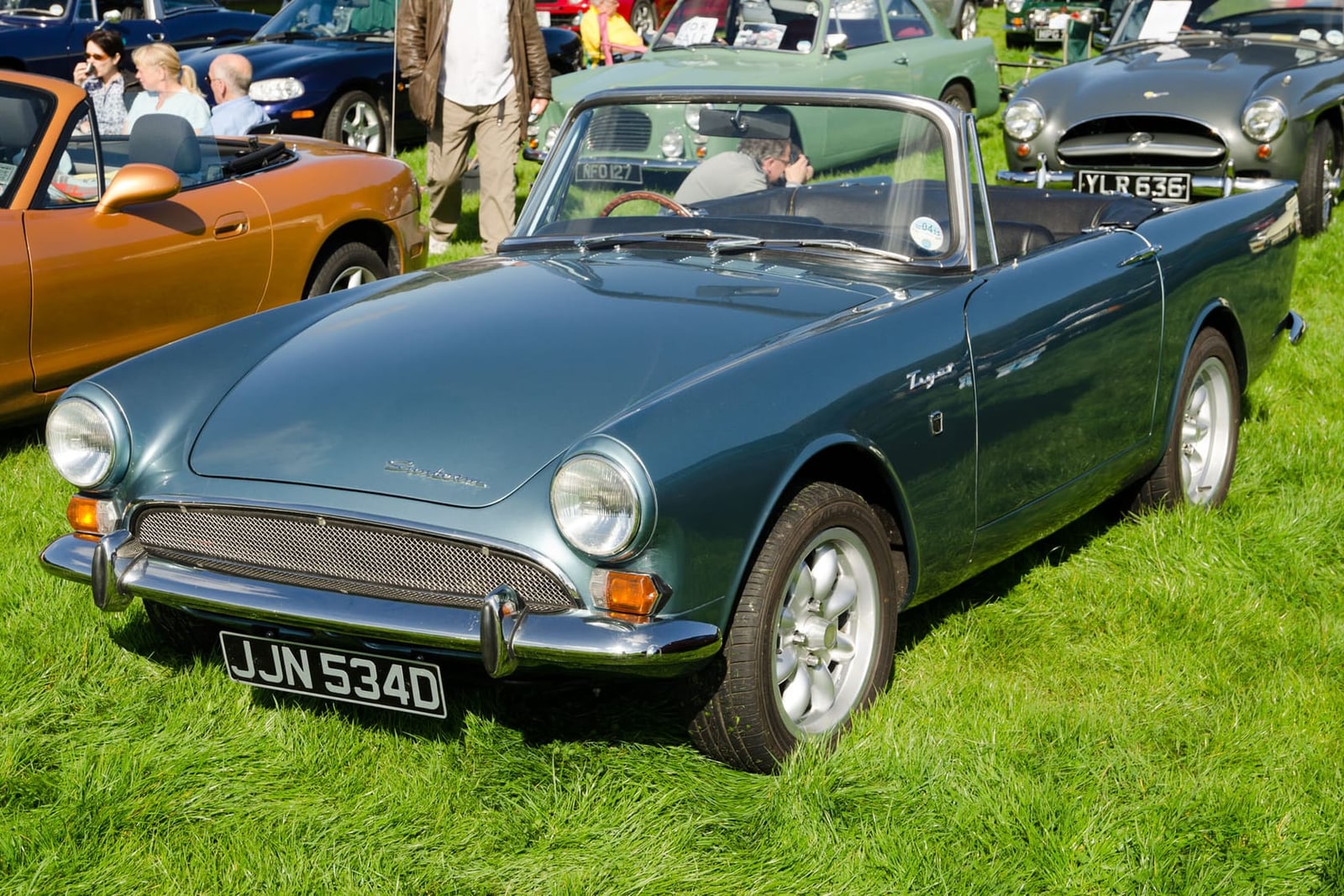 A blue-grey 1966 Sunbeam Tiger on grass, front three-quarter view, UK registration JJN 534D