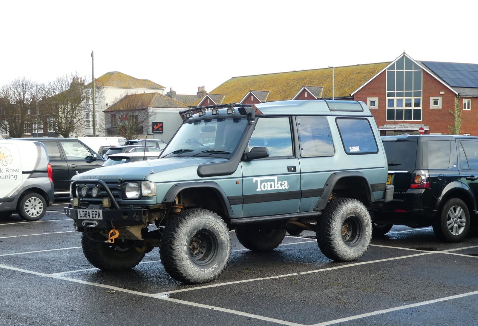 A pale green 1994 Land Rover Discovery Tonka special edition with roof rack and chunky tyres in a seaside car park