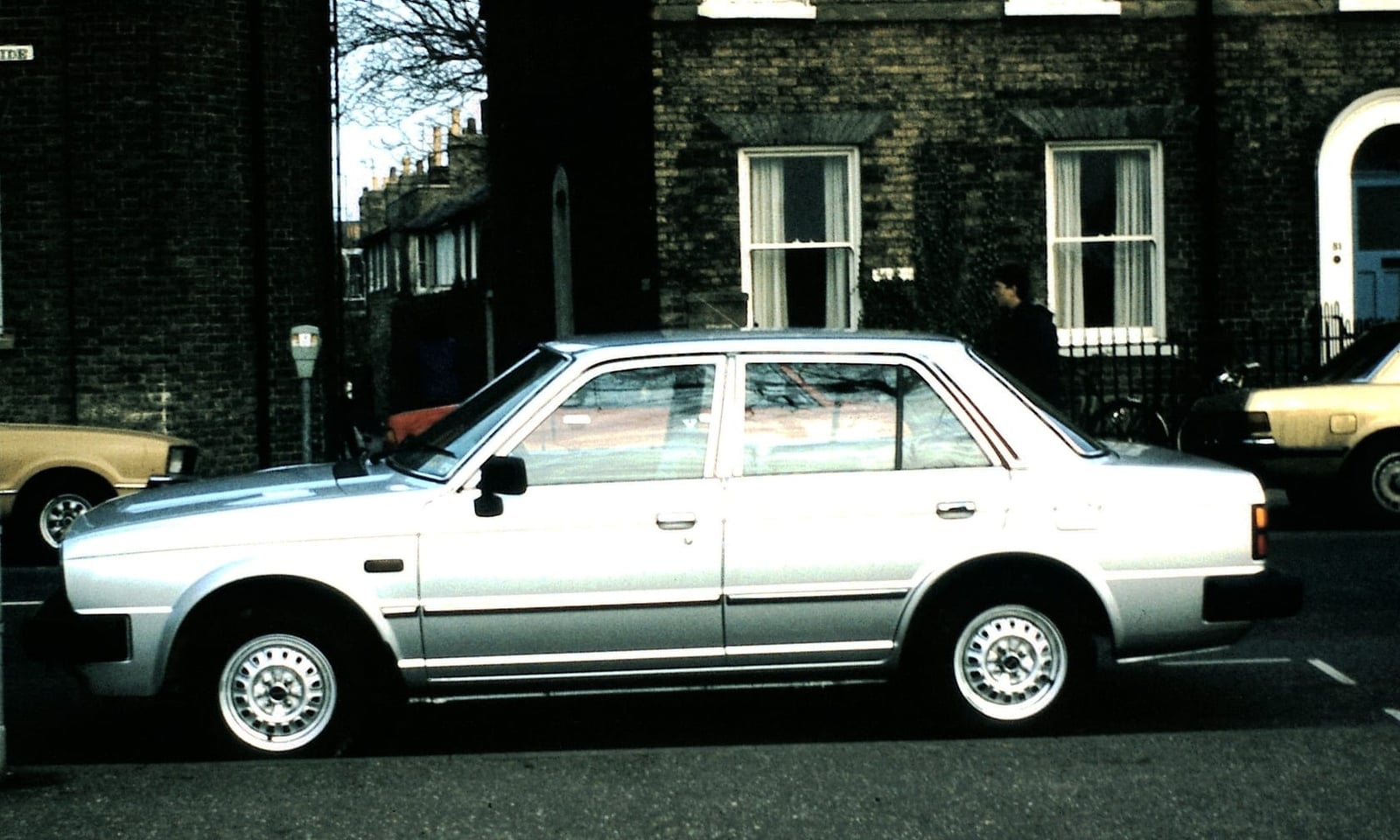 A silver Triumph Acclaim parked on a London terraced street in period, side view