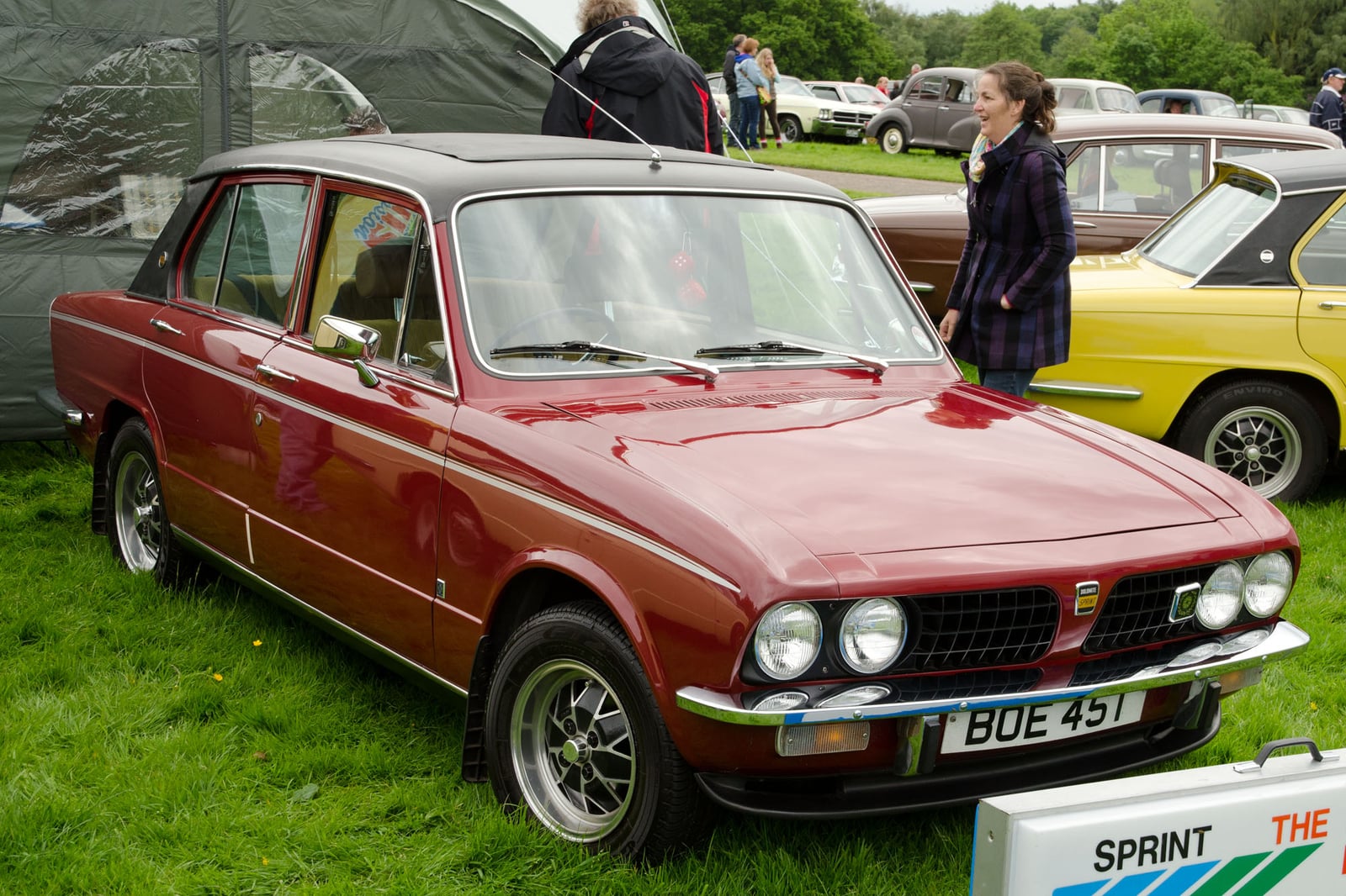 A maroon Triumph Dolomite Sprint with a black vinyl roof, front three-quarter view on grass