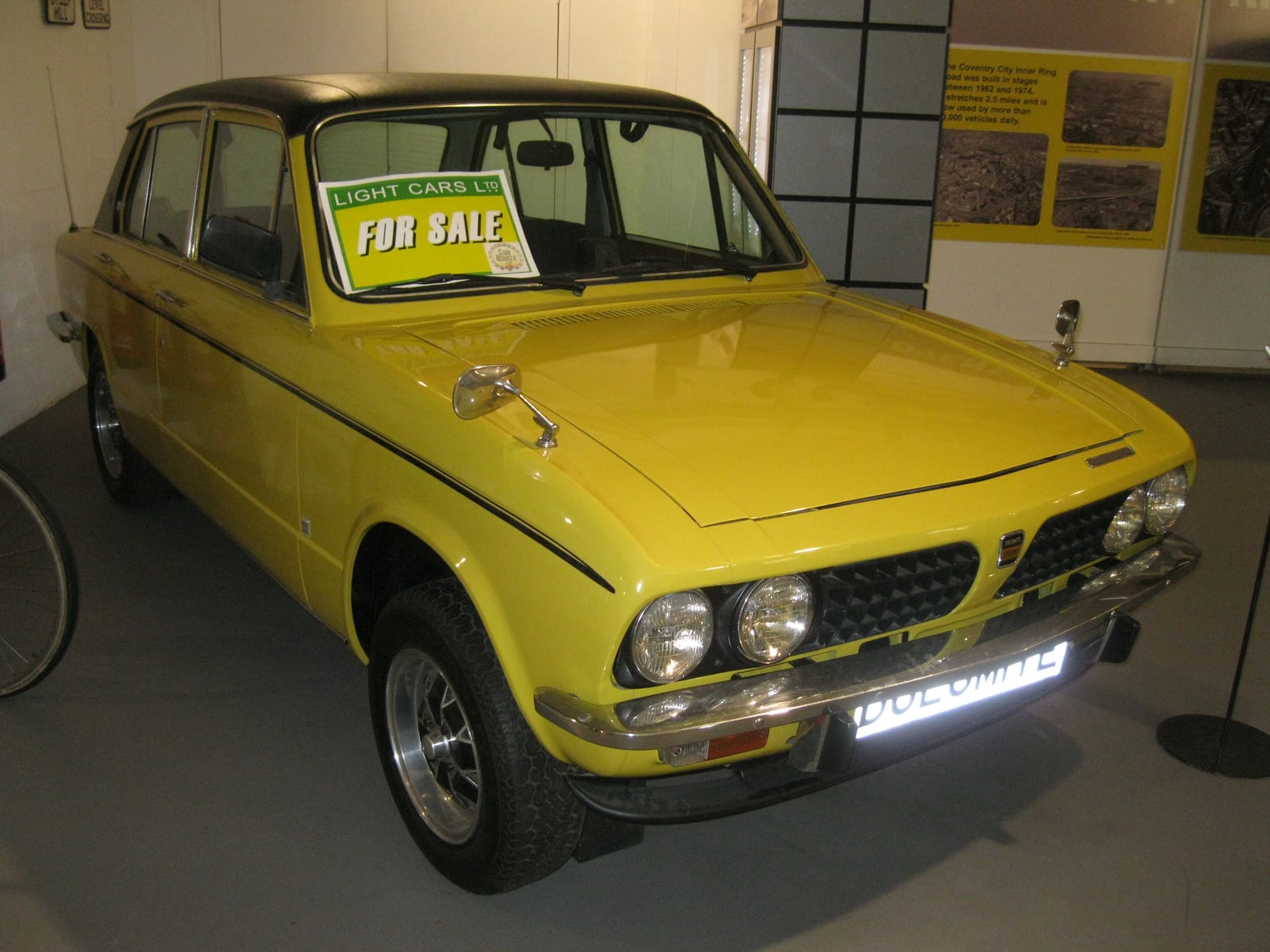 A yellow Triumph Dolomite Sprint on display indoors at a museum