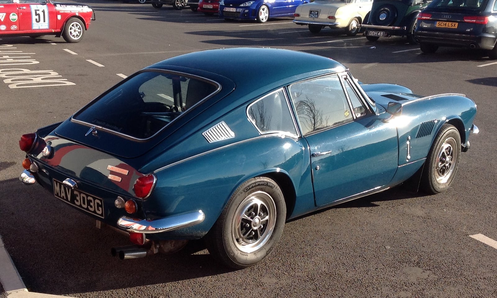 A dark teal Triumph GT6 Mk2 fastback coupe, rear three-quarter view