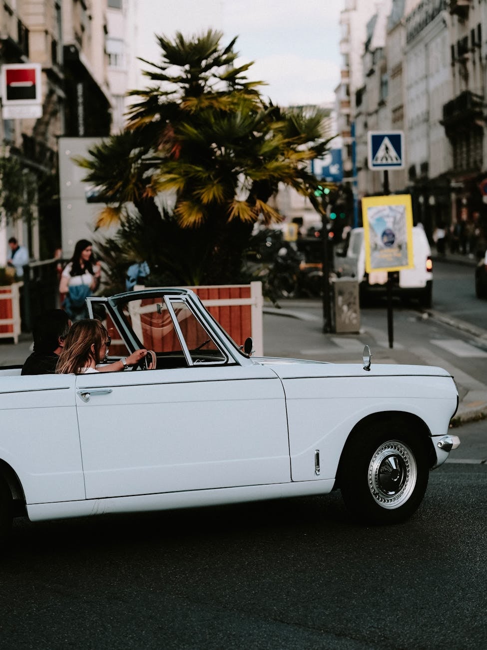 A cream Triumph Herald convertible with the top down on a city street