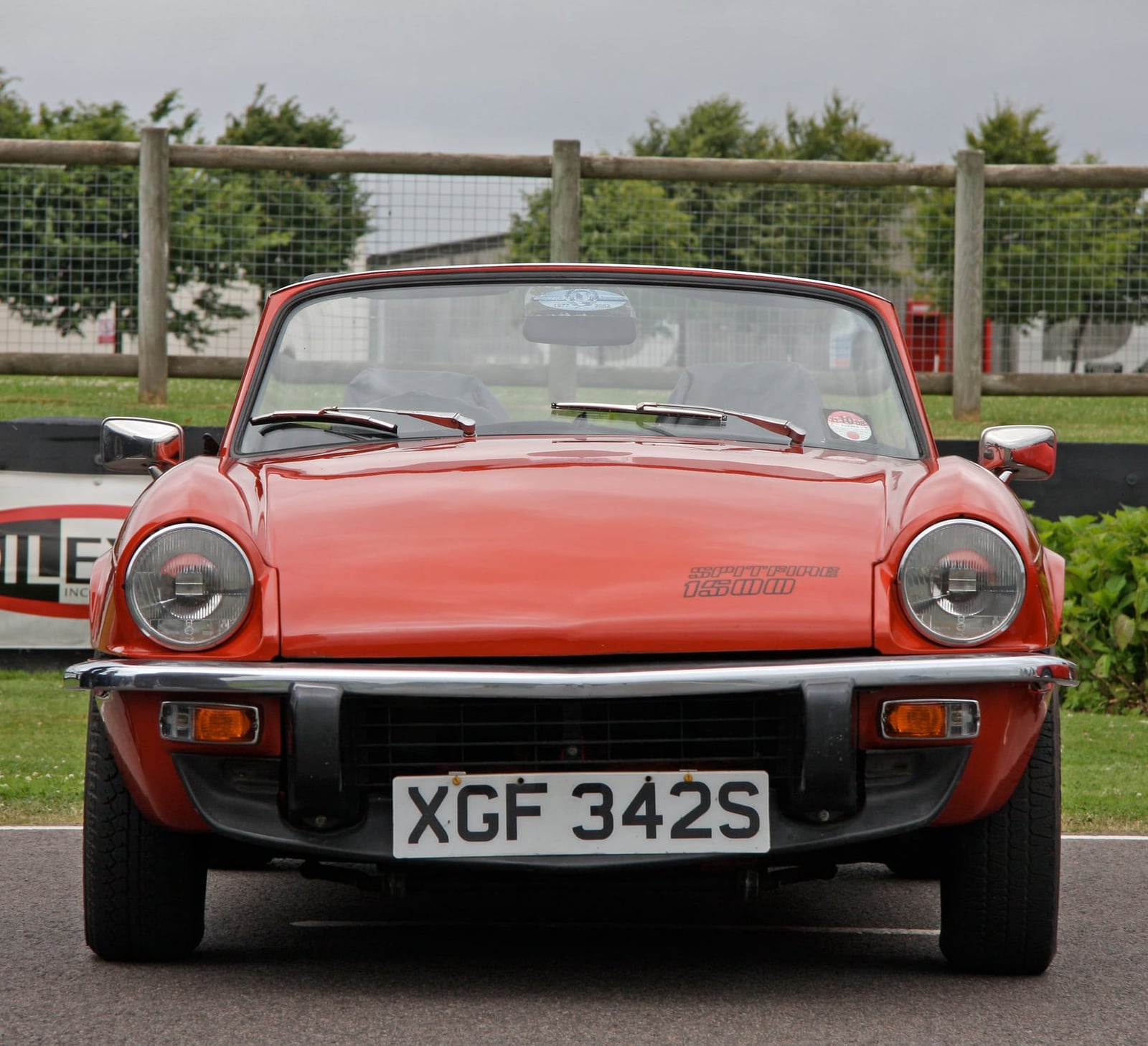 An orange Triumph Spitfire 1500 with a UK registration, seen head-on at a circuit