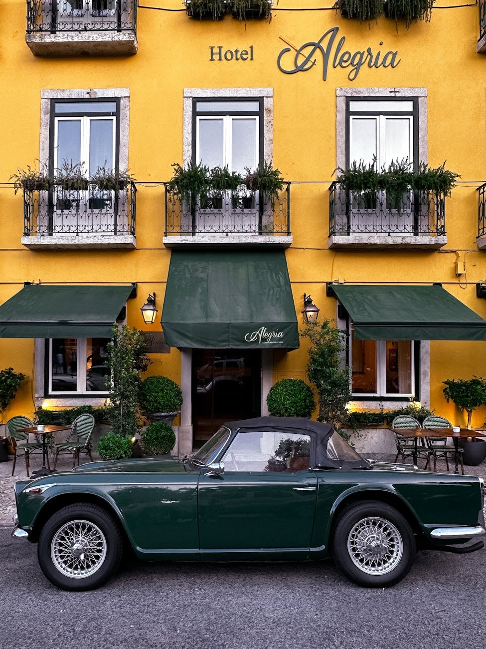 A green Triumph TR4, side view, parked outside a building