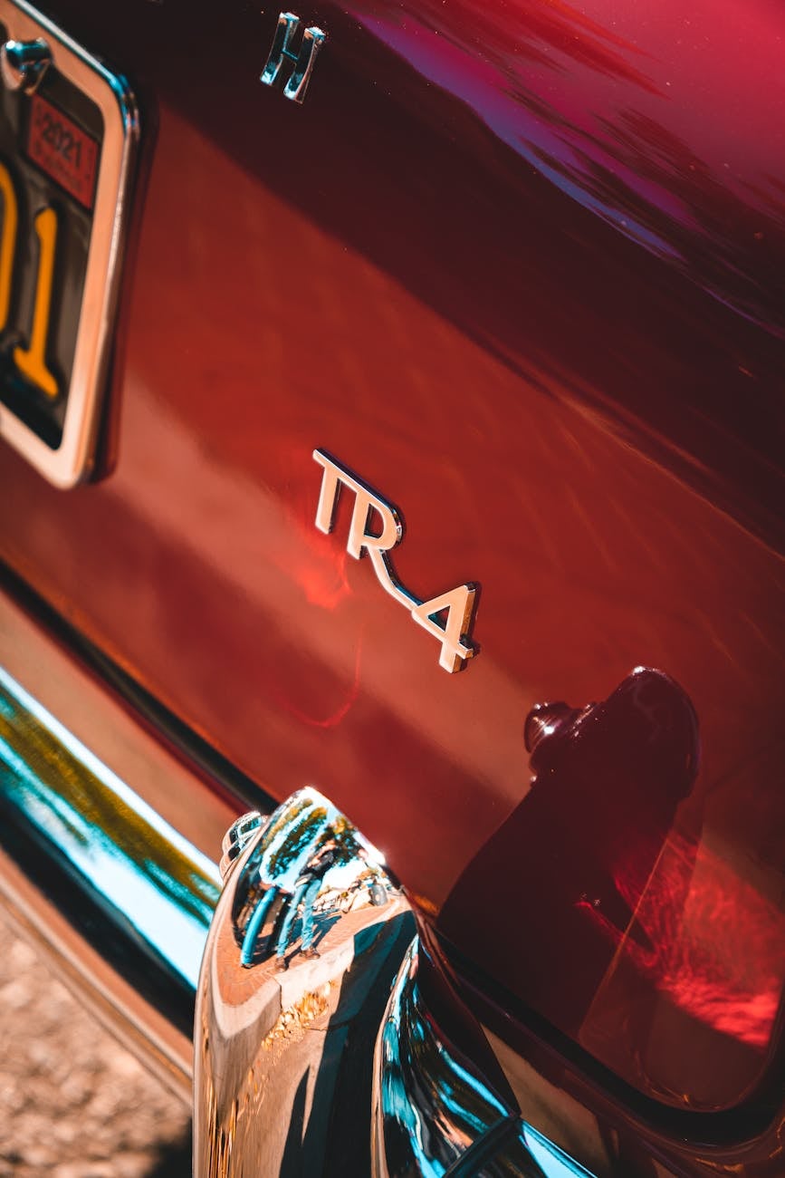 Close-up of the chrome TR4 script badge on the red rear panel of a Triumph TR4