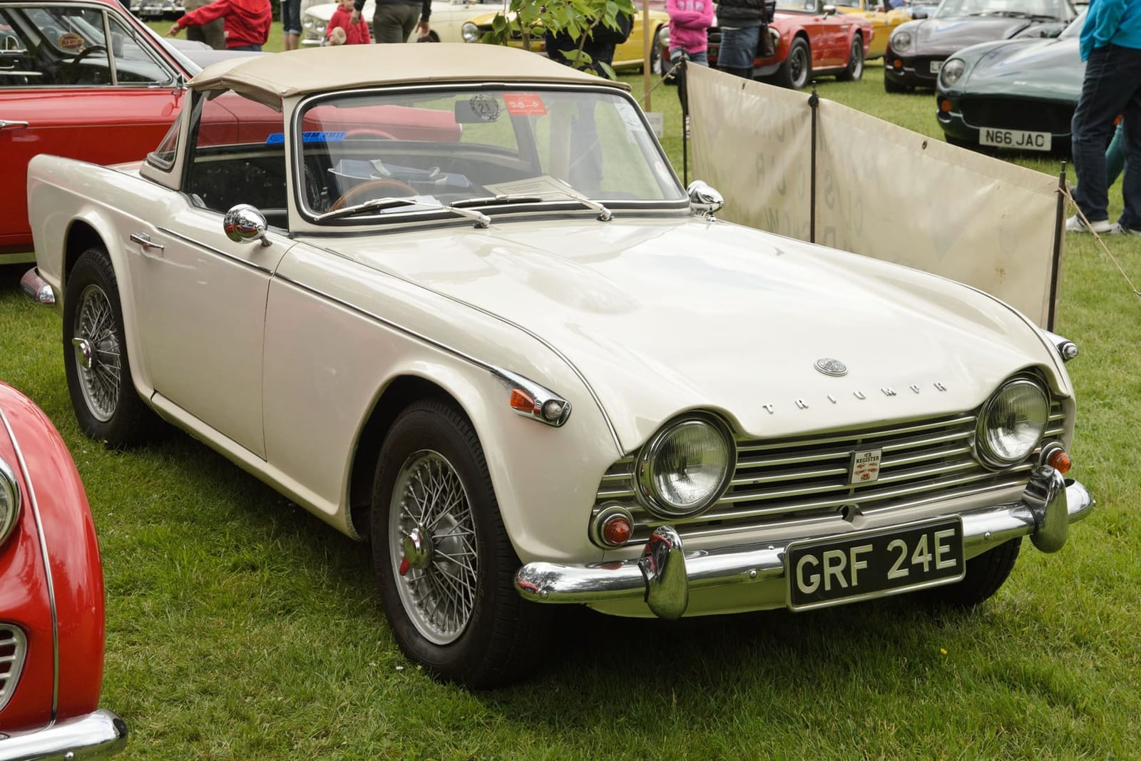 A cream 1967 Triumph TR4A with a beige hood, wire wheels and a UK registration at a show