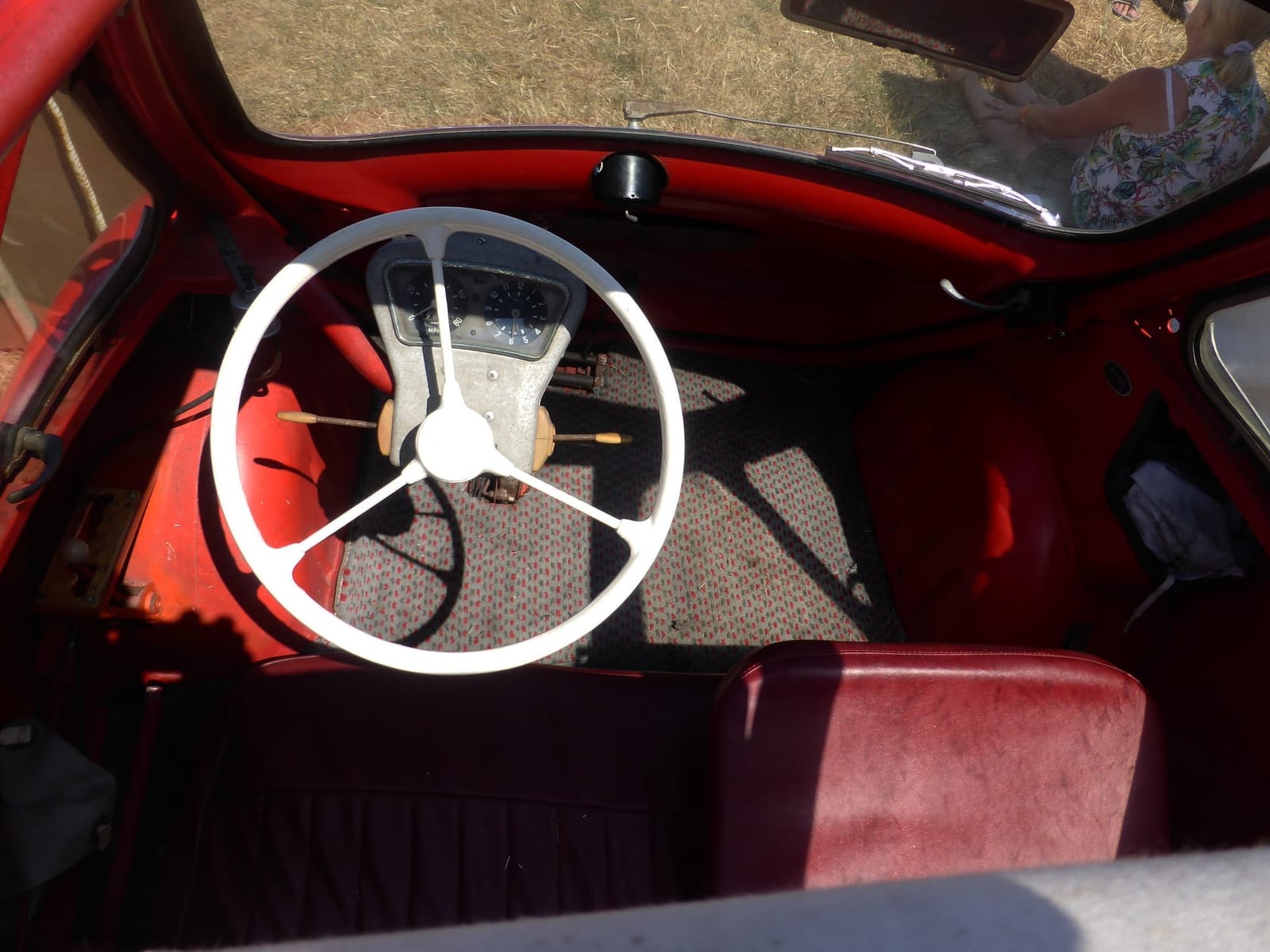 A red Trojan 200 bubble car on grass at a classic vehicle show, rear three-quarter view, UK registration 566 LJH