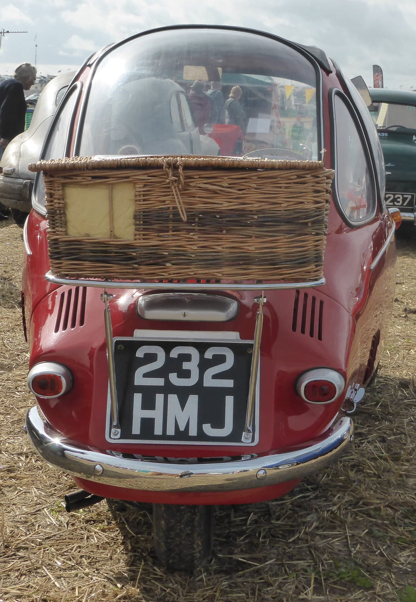 An orange Trojan Heinkel bubble car on indoor display with its single front door swung open