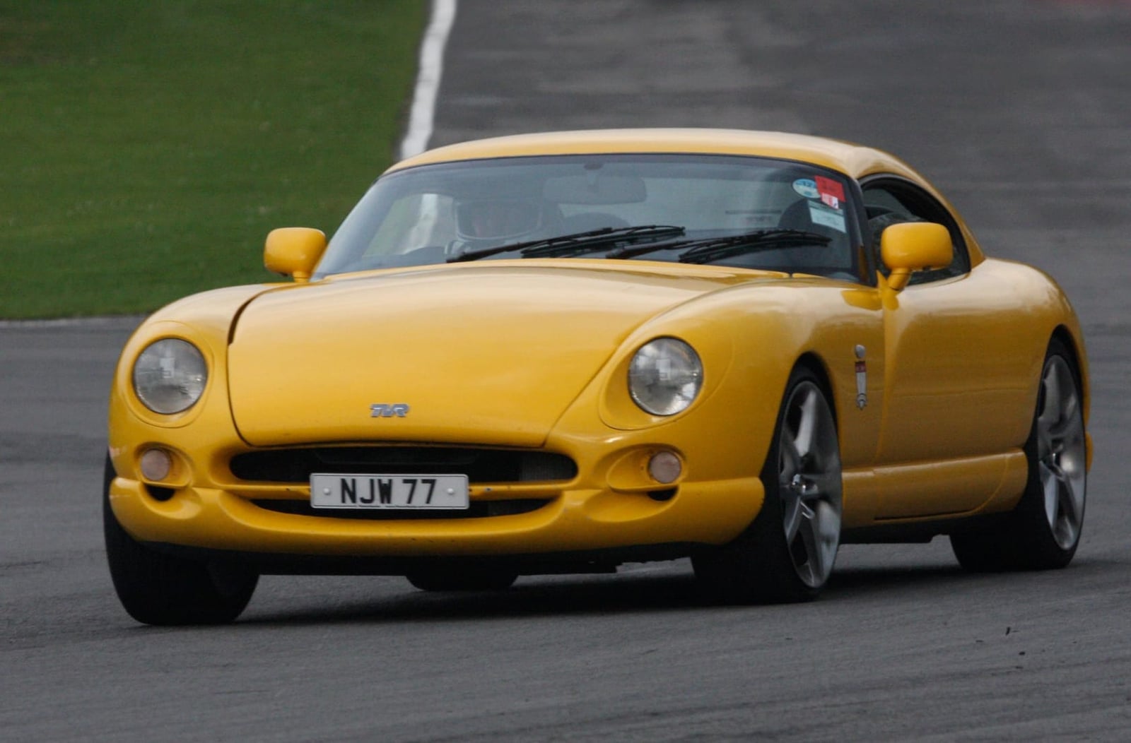 A yellow TVR Cerbera 4.5 with UK registration NJW 77 cornering on a race circuit