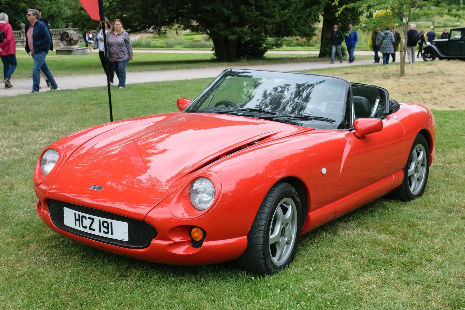 A red 1996 TVR Chimaera with the hood down on grass at a classic car show, front three-quarter view, UK registration HCZ 191