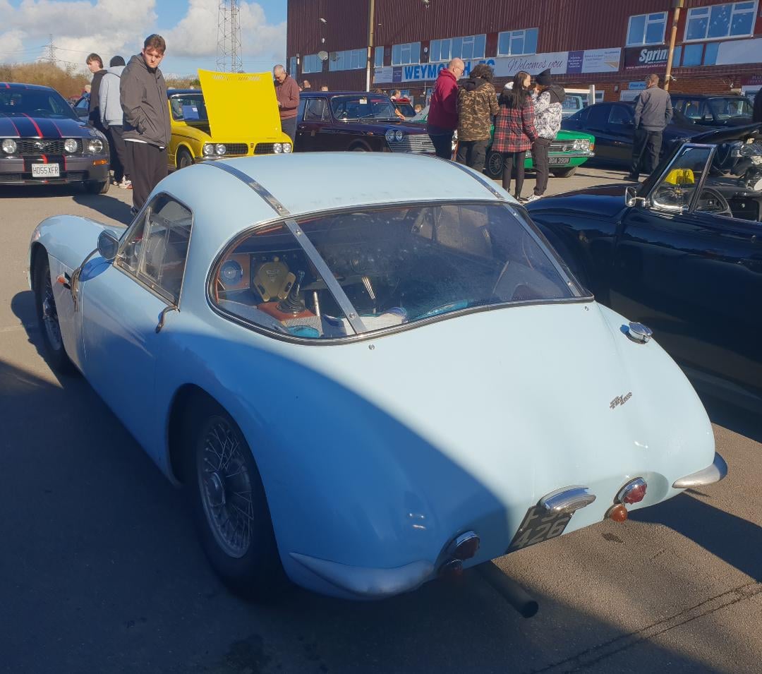 A light blue TVR Grantura Mk 1 rear three-quarter view at a classic car show