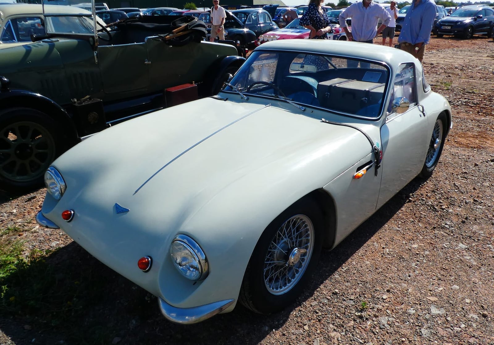 A pale green 1959 TVR Grantura Mk 1 parked on gravel among classic cars