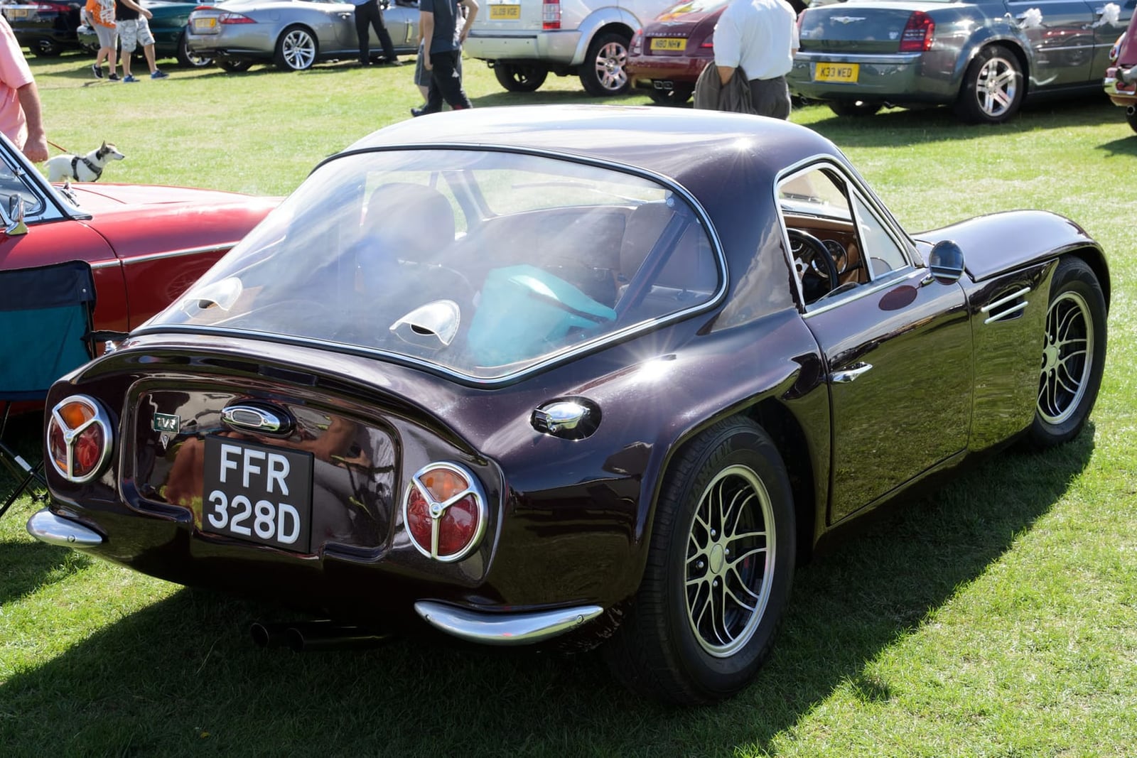 The rear three-quarter view of a dark maroon 1966 TVR Griffith 400 with UK registration FFR 328D