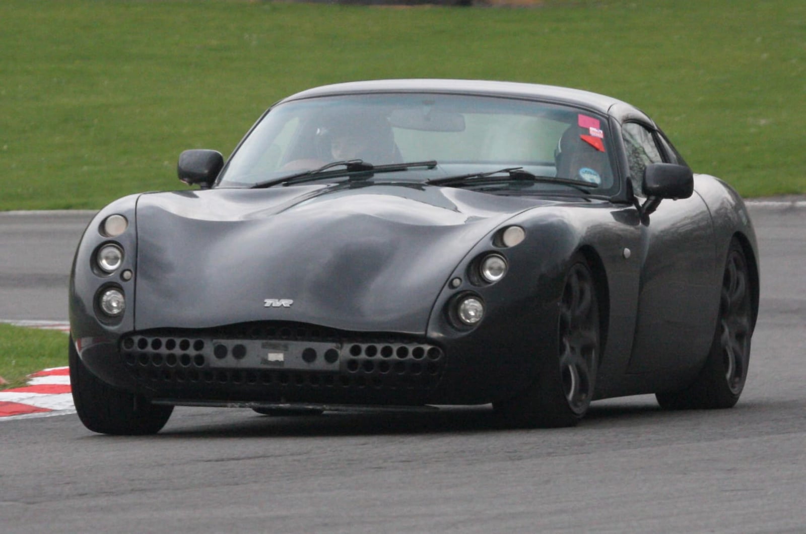 A black TVR Tuscan cornering on a race circuit