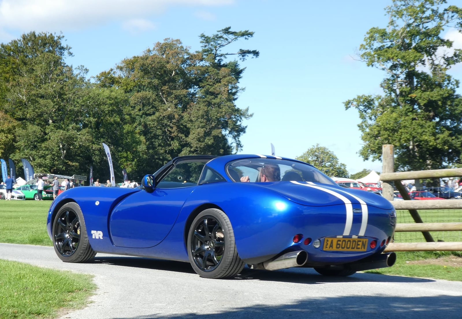 A blue TVR Tuscan Speed Six with white stripes on a show field among trees
