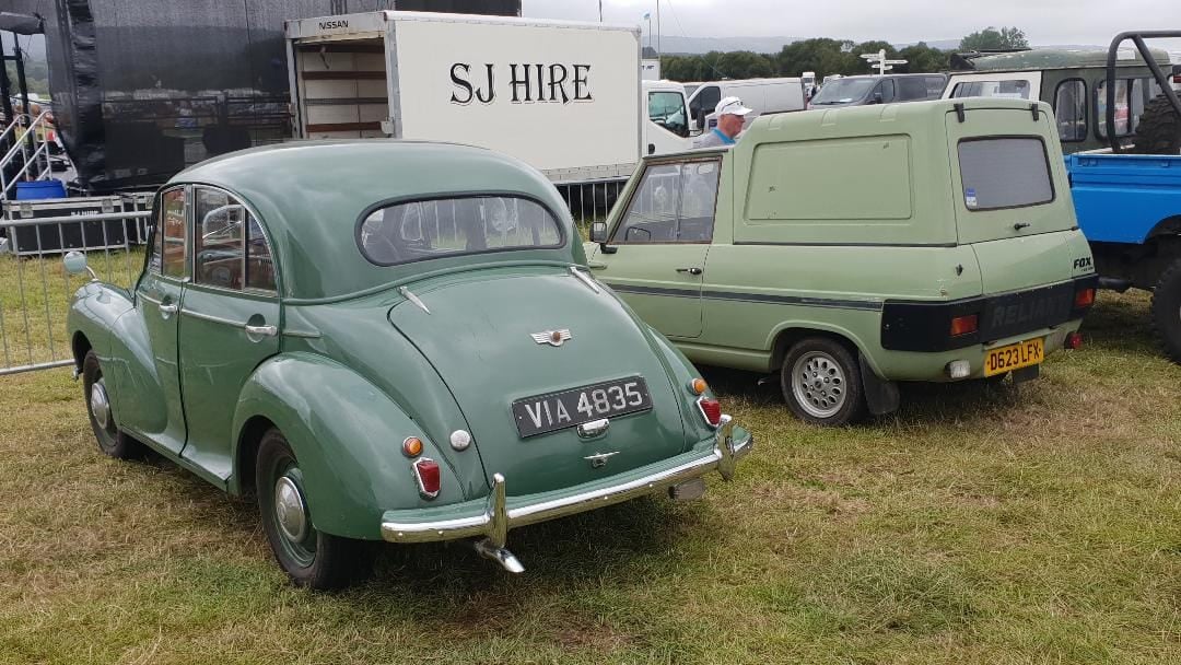 A green Morris Minor and a green Reliant Fox van parked together at a vehicle show
