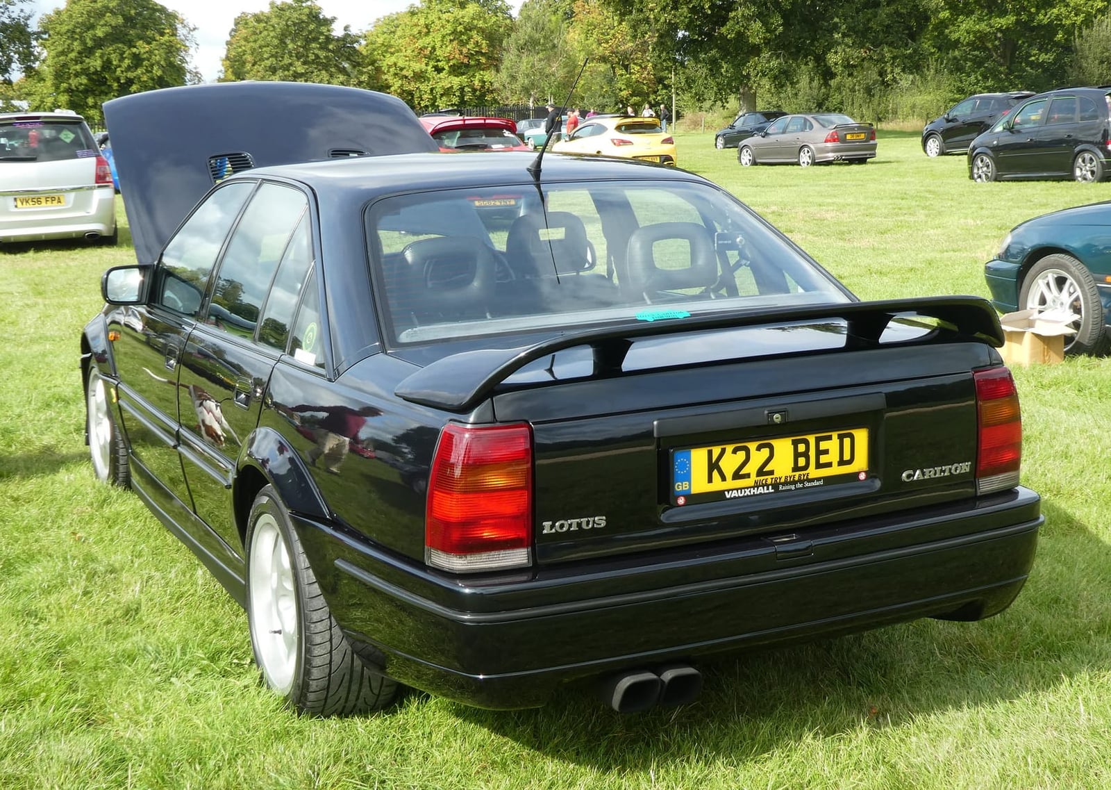 The rear three-quarter of a dark green Lotus Carlton on grass at a show, UK registration K22 BED